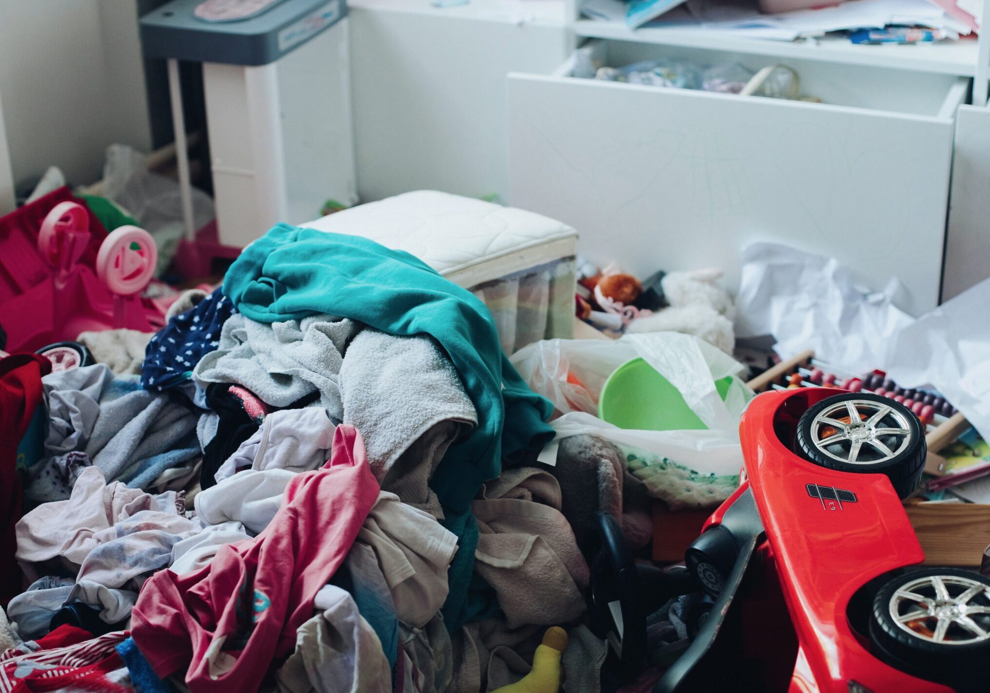 Messy room and disorder concept in the living room or bedroom. Scattered clothes and stuff on the floor.